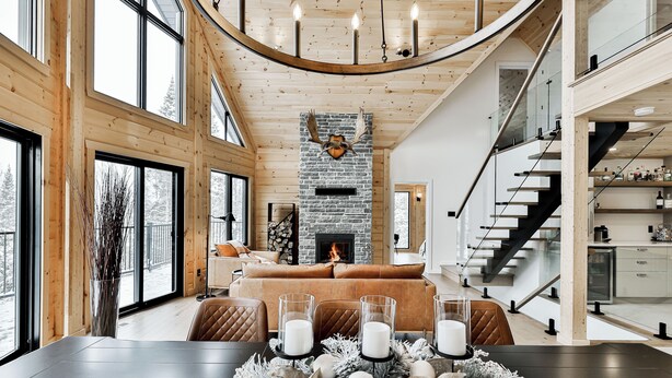 A spacious living area with a fireplace, a dining table set with candles, and a staircase leading to an upper level. - Magnificent ski-in/out wooden chalet in Mont-Blanc with SPA and billiard table! (Mont-Blanc)
