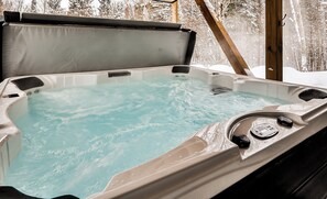 Relax in a serene outdoor hot tub, surrounded by a peaceful forest setting.