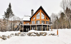 Guests can enjoy a cozy stay in this cabin-style house with a gable roof, large windows, and a covered porch.