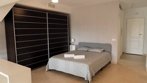 A bedroom with a bed, a wardrobe, a ceiling fan, and a door. - La Envia Golf Suite (Vícar)