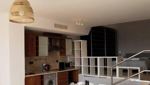 A modern kitchen with a dining area, a staircase, and a laundry room. - La Envia Golf Suite (Vícar)