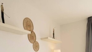 A modern living room with a grey sofa, a white coffee table, and decorative woven wall art. - La Envia Golf Suite (Vícar)
