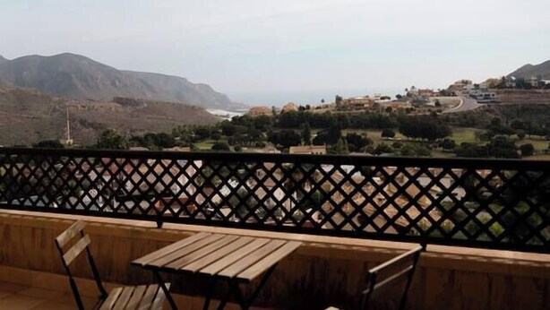 A terrace with a wooden table and chairs, overlooking a mountainous landscape. - La Envia Golf Suite (Vícar)