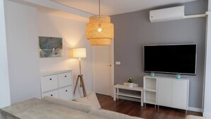 Ein modernes Wohnzimmer mit einer Couch, einem Fernseher, einer Lampe und einem Gemälde an der Wand.