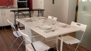 A compact kitchen with white cabinets, a microwave, and a red tiled backsplash. - Puerta Real Apartments (Granada)