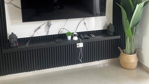 Una sala moderna con un televisor de pantalla plana grande montado en una pared negra con paneles acústicos.