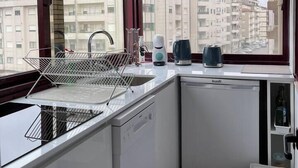 A compact kitchen with a dishwasher, a kettle, and a coffee maker on the counter. - Nice apartment in Gaia next to Bodegas (Vila Nova de Gaia)