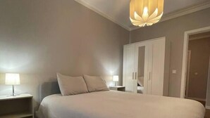 A bedroom with a large bed, a wardrobe, a nightstand, and a hanging light fixture. - Nice apartment in Gaia next to Bodegas (Vila Nova de Gaia)