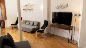 A modern living room with a grey sofa, black armchairs, a wooden TV stand, and a mounted TV. - To complete (Granada)