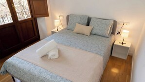 A neatly made bed with a patterned duvet, two bedside lamps, and a rolled towel on the bed. - To complete (Granada)