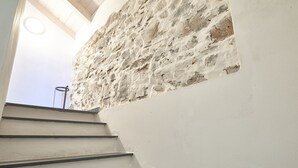 Una escalera que sube hacia un muro de piedra con un tragaluz circular.