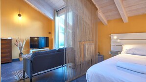 Un dormitorio con cama, sofá, televisión y un amplio ventanal.