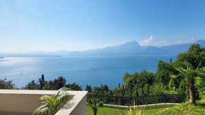 Eine Küstenansicht mit blauem Himmel, einem Gewässer und fernen Bergen.