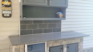 Una cocina con gabinetes grises, un salpicadero de azulejos y una encimera de piedra.