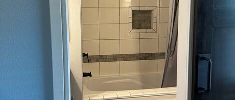 A bathroom with a bathtub, shower, and toilet.