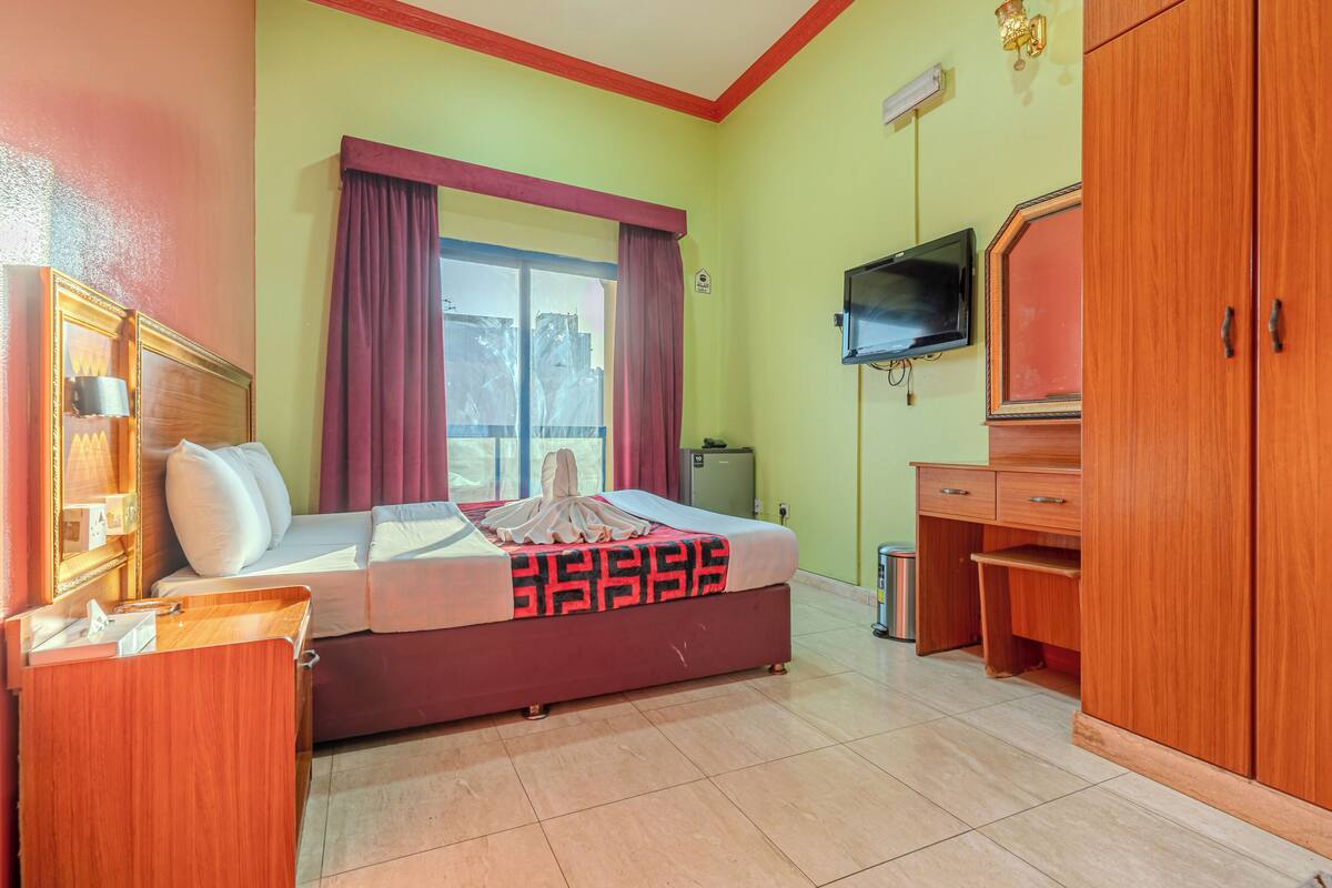 A hotel room with a bed, a desk, a television, and a wardrobe.