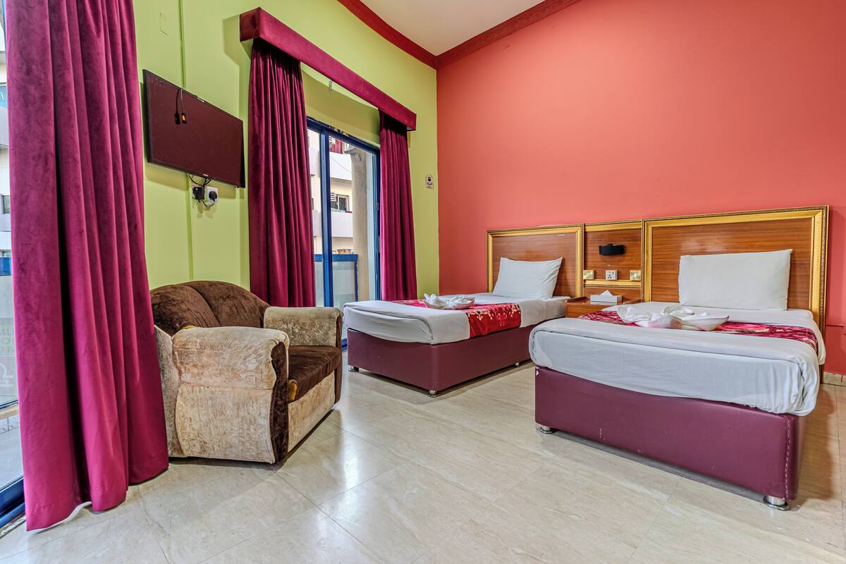 A hotel room with two beds, a sofa, and a TV.