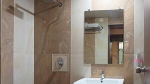 Un baño con ducha, lavamanos y espejo.