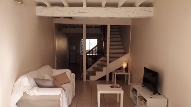 Ein Wohnzimmer mit einer Couch, einem Couchtisch, einem Fernseher und einer Treppe, die in einen anderen Raum führt.