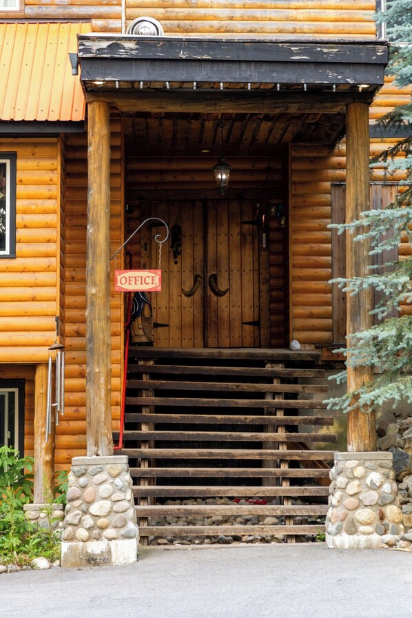 A wooden log cabin with a sign reading "OFFICE" above the entrance.