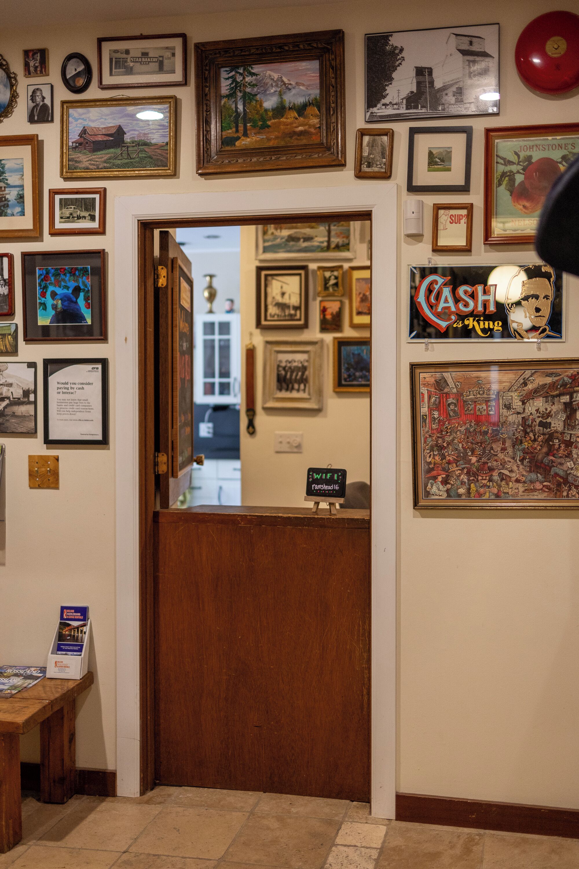 A room with a wooden door, framed pictures on the walls, and a 'Cash is King' sign.