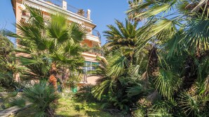 A multi-story building with balconies, surrounded by lush greenery and palm trees. - Green Home Seaside Parking  Wifi Ac Genova (Genoa)