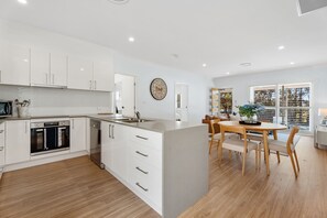 A modern kitchen with white cabinetry, a built-in oven, and a dishwasher.