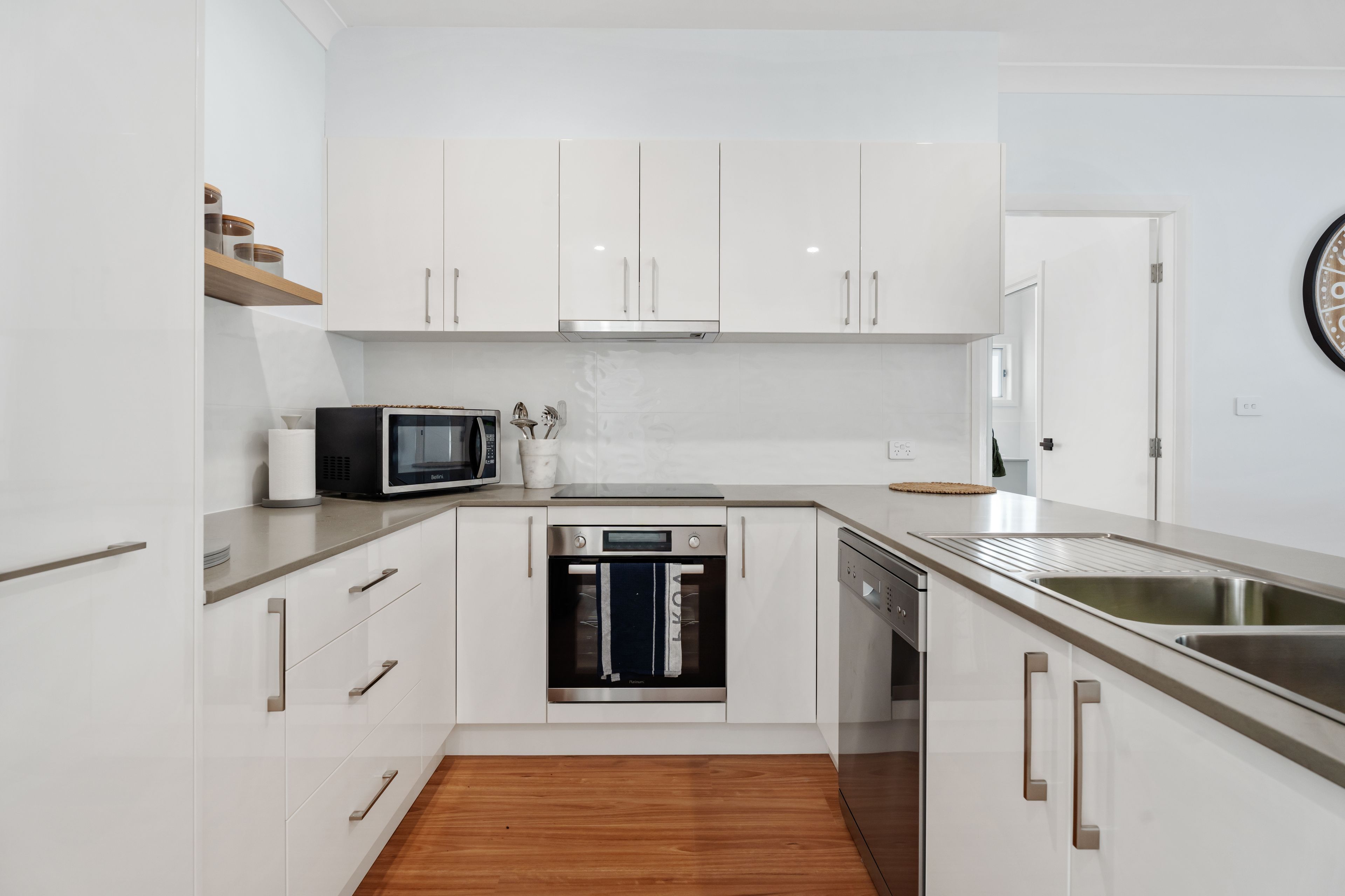 Une cuisine moderne avec des meubles blancs, un four à micro-ondes, un four traditionnel et un lave-vaisselle.