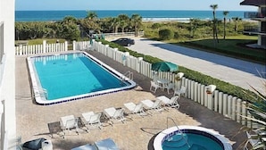 A rectangular swimming pool with a small hot tub, surrounded by lounge chairs and a white fence. - Ocean's Edge Retreat- Direct Ocean 2 Bed/2Bath (Cape Canaveral)