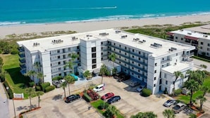 A multi-story hotel with a flat roof, parking lot, and a view of the beach and ocean. - Ocean's Edge Retreat- Direct Ocean 2 Bed/2Bath (Cape Canaveral)