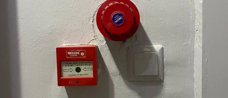 Un detector de incendios y un interruptor de luz fijados a la pared.
