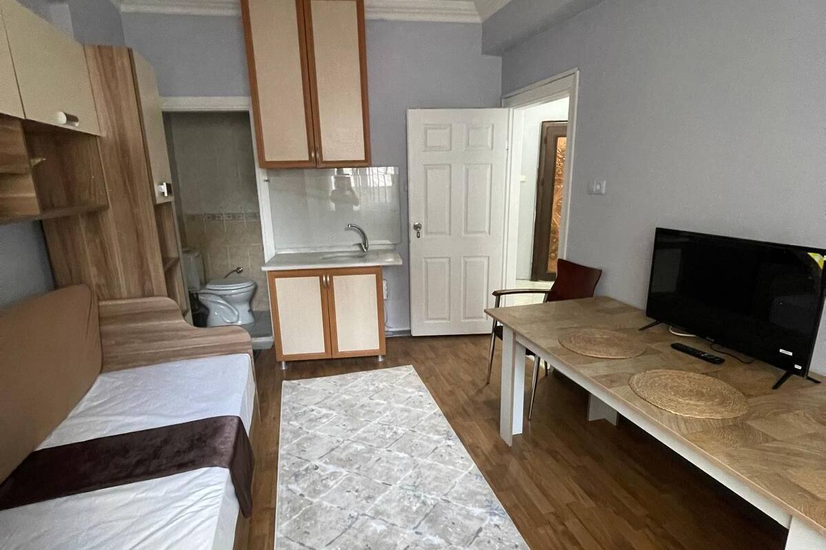 Un espacio habitable compacto con kitchenette, comedor y televisor.