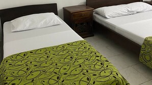 Een hotelkamer met twee bedden, een nachtkastje en twee lijstwerken met landschappen aan de muur.