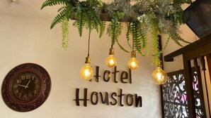 Een muur met een klok en de tekst 'Hotel Houston' erboven.