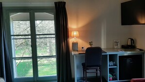 Une chambre d’hôtel équipée d’un bureau, d’une chaise et d’un téléviseur fixé au mur.