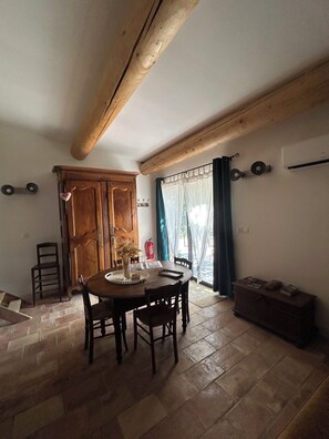 A dining area with a wooden table and chairs, a wooden cabinet, and a window with curtains.