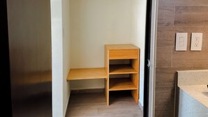 A corner of a room with a wooden shelf unit, a door, and a wall with two electrical outlets. - El Pacifico (La Libertad)