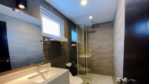 A modern bathroom with a large sink, toilet, and glass shower enclosure. - El Pacifico (La Libertad)