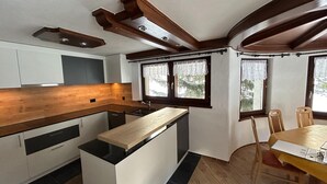 Une cuisine moderne avec un plan de travail en bois, des armoires blanches et un coin repas comprenant une table et des chaises.