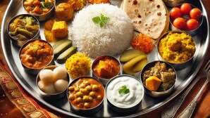 A traditional Indian meal with various dishes, including rice, curries, and flatbreads, served on a metal plate. - Hotel Aaarav Grand - Mathura Vrindavan (Mathura)