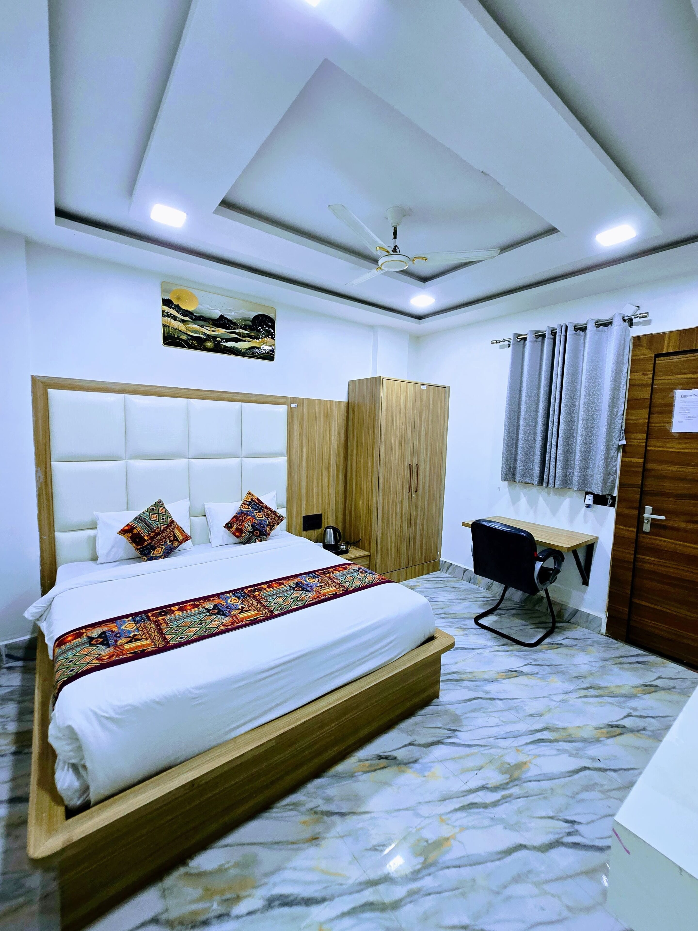 Une chambre à coucher comprenant un lit, un bureau, une armoire et un ventilateur de plafond.