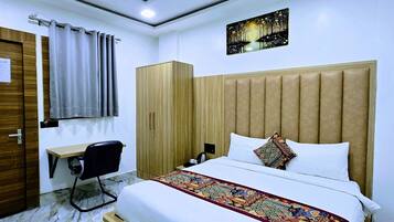Habitación de hotel con cama, escritorio, silla, armario y ventilador de techo.