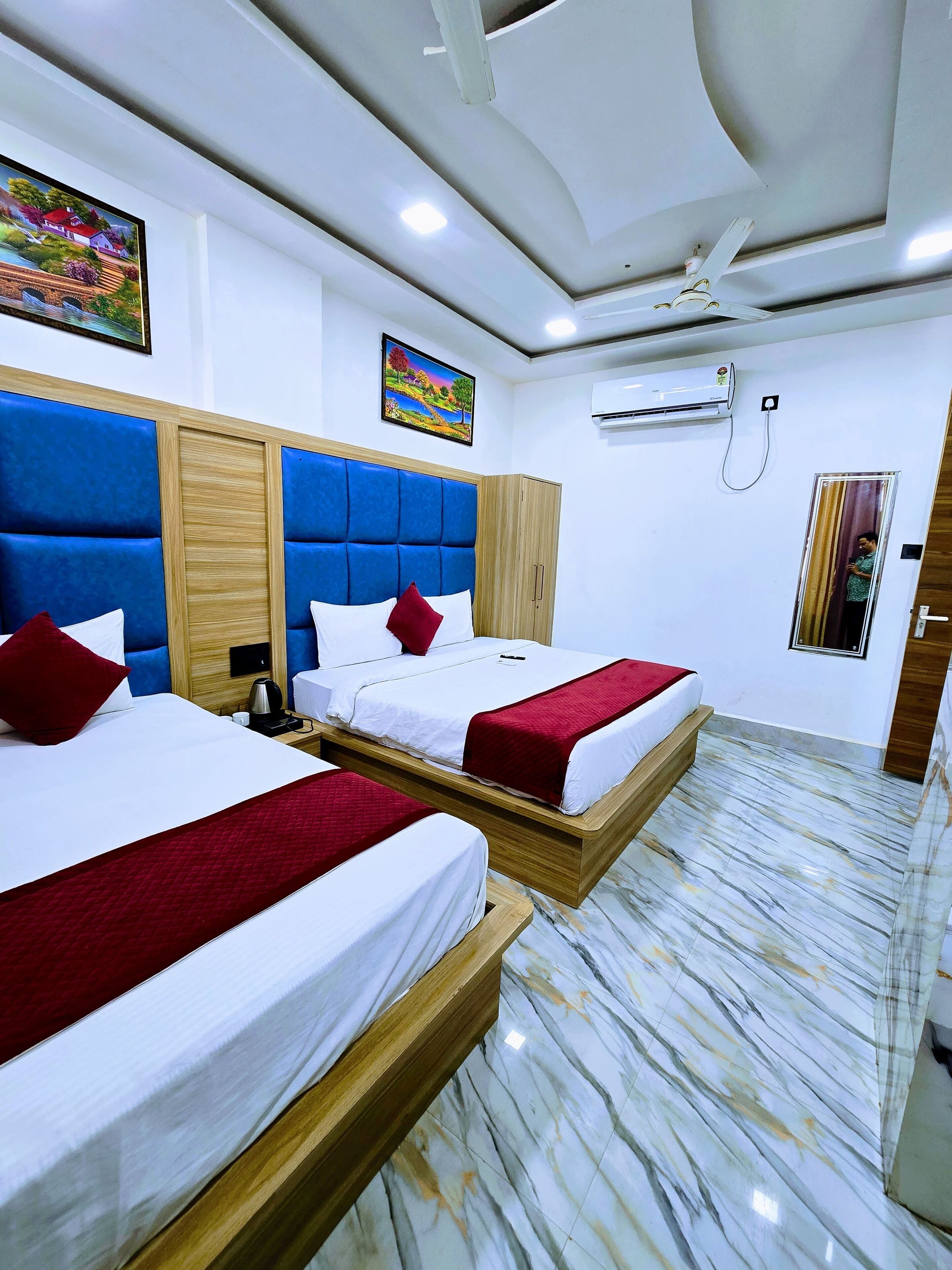 A hotel room with two beds, a wooden headboard, a marble floor, and an air conditioning unit.