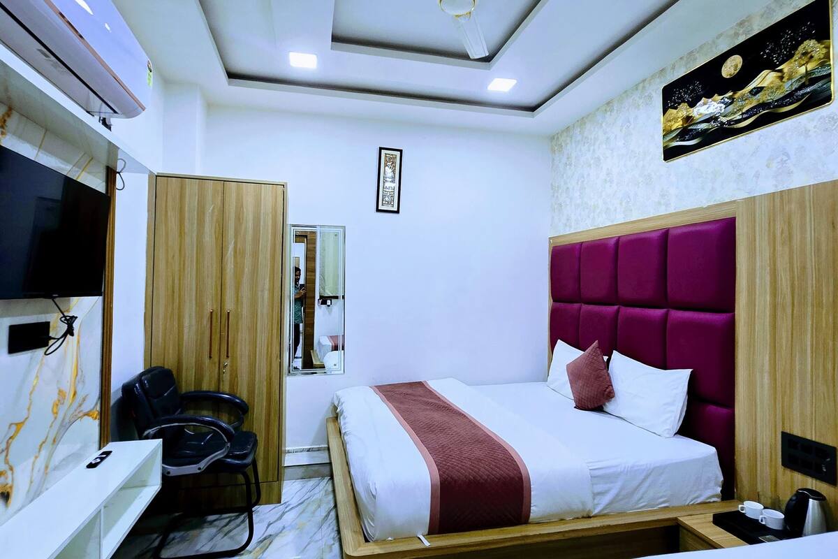 Una habitación de hotel con una cama, un escritorio, una silla, un televisor y un ventilador de techo.