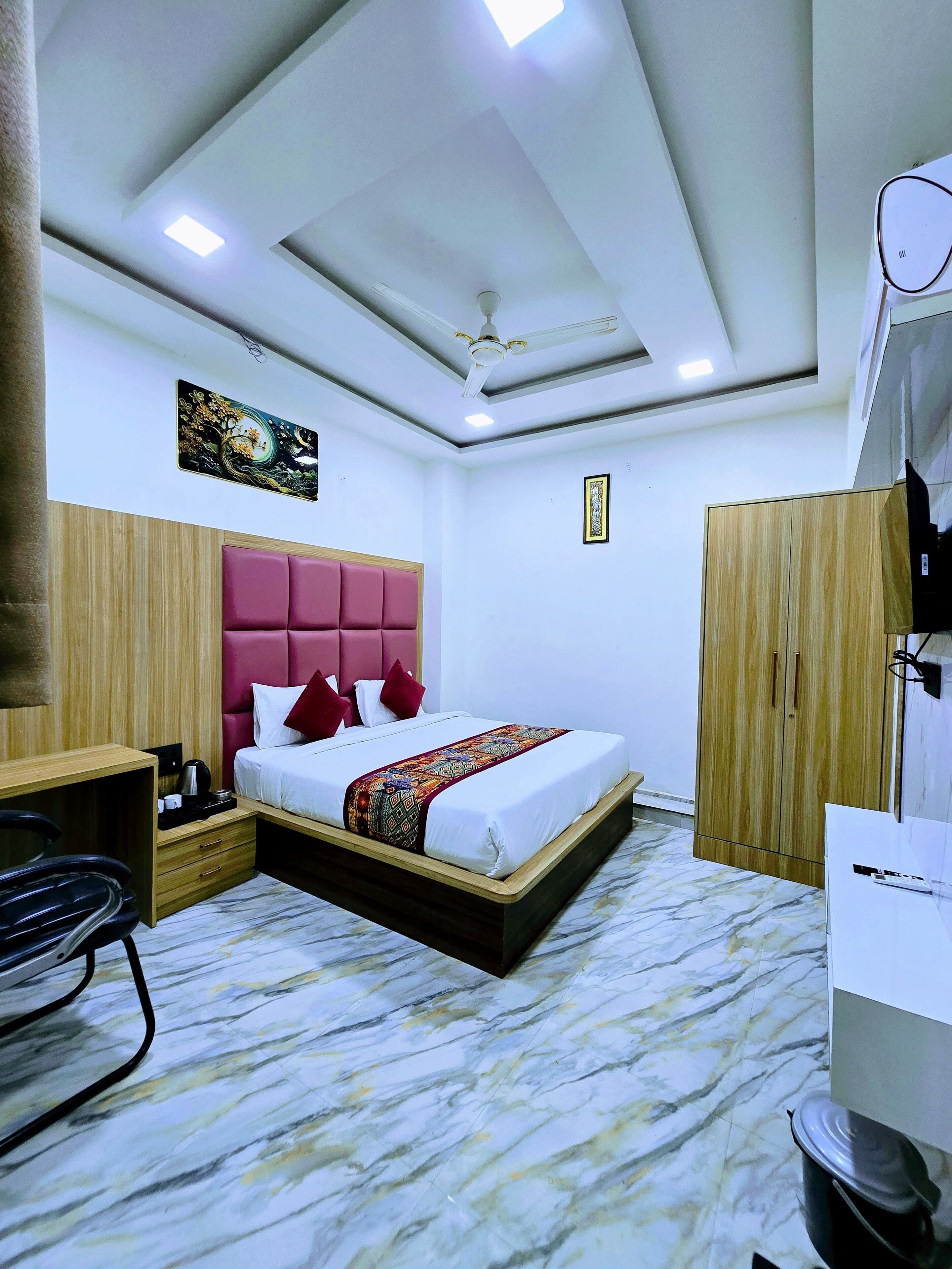 Une chambre d’hôtel équipée d’un lit, d’un bureau, d’une armoire et d’un ventilateur de plafond.