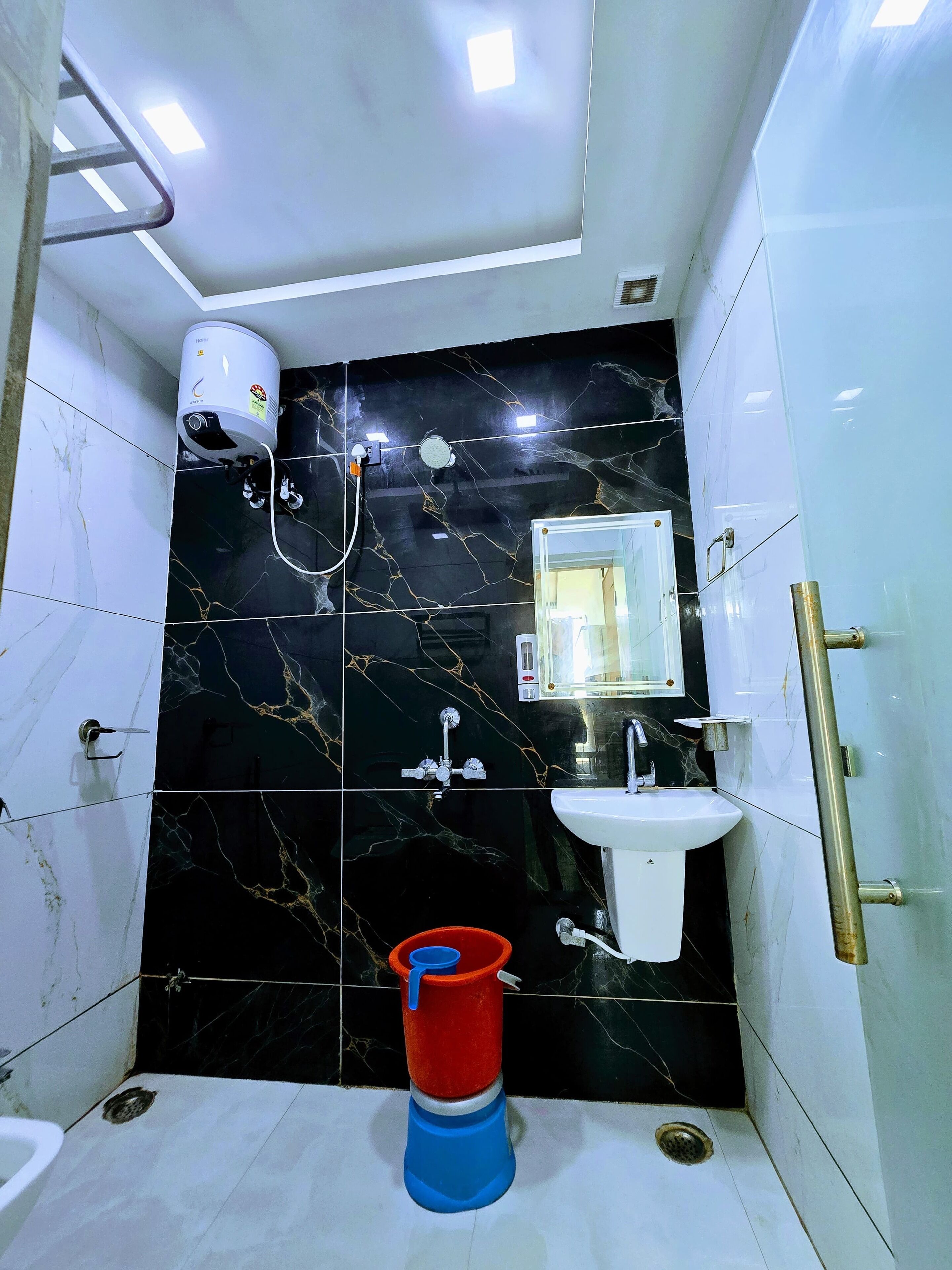 Un baño con salpicadero de mármol negro, un lavabo blanco, un espejo, una ducha y un inodoro.