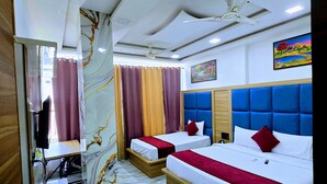 A hotel room with two beds, a TV, a ceiling fan, and a painting on the wall. - Hotel Aaarav Grand - Mathura Vrindavan (Mathura)