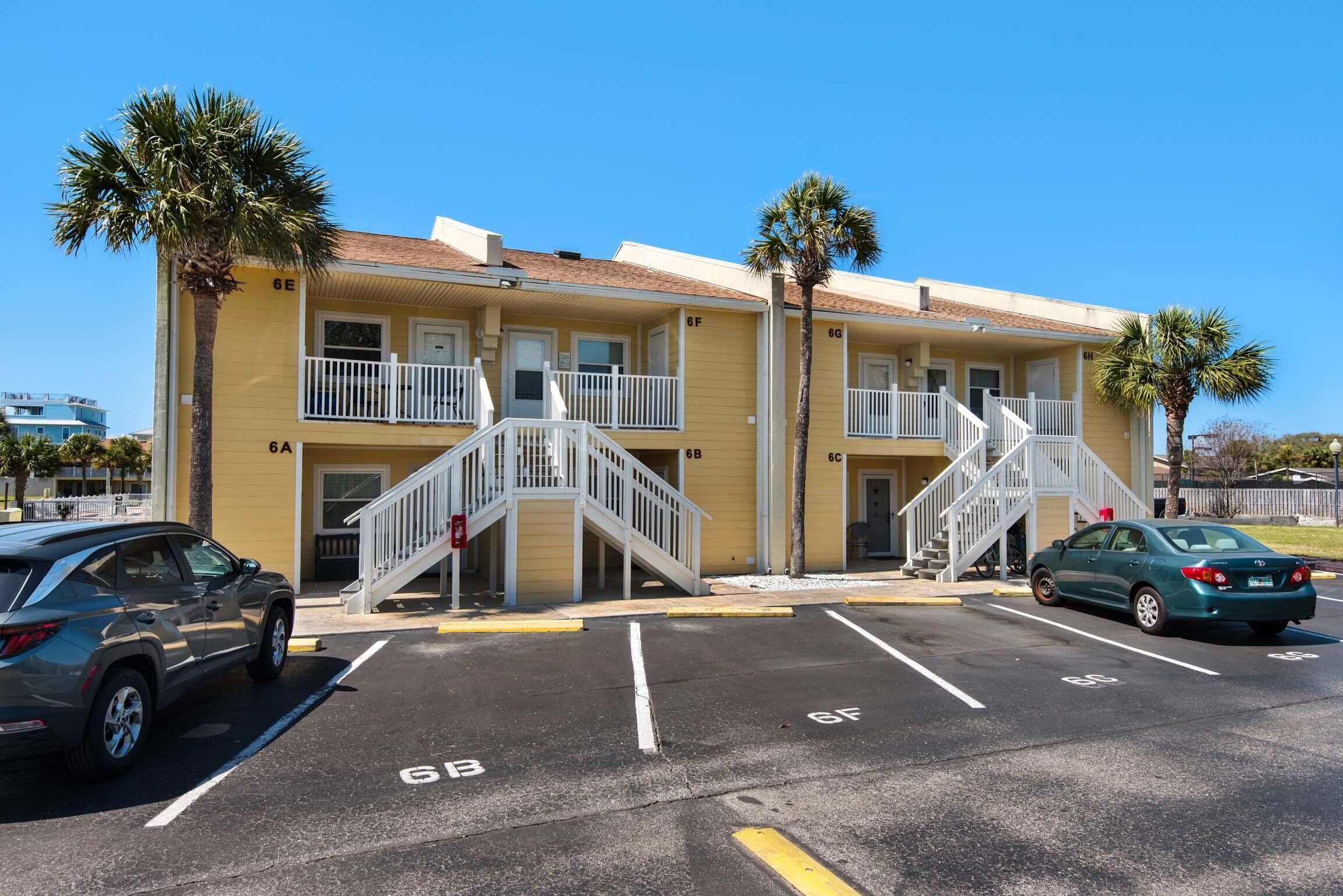 Un motel jaune avec des balcons à deux étages, un parking et des palmiers.