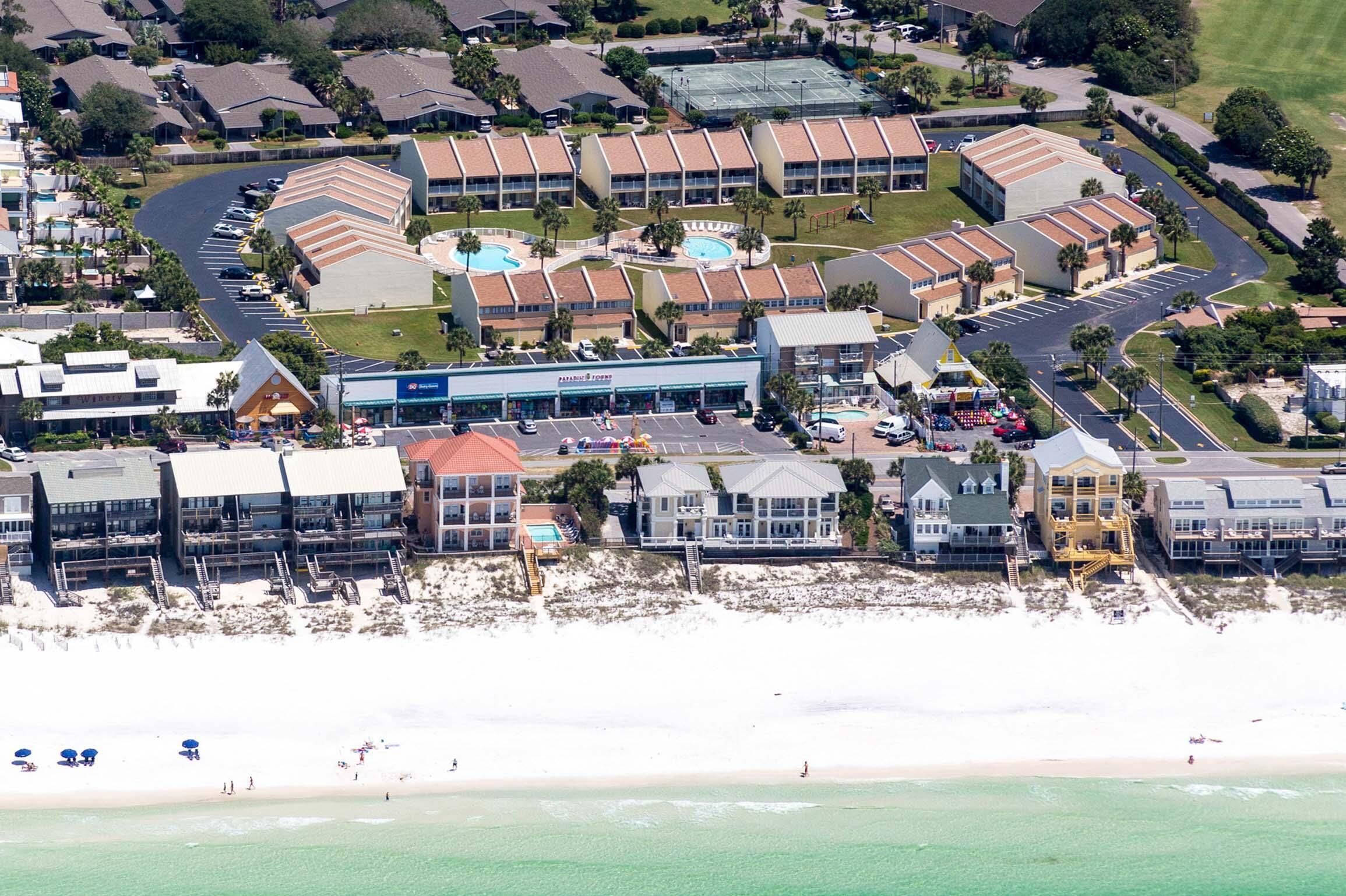 Vue aérienne d’un hôtel situé sur la côte, composé de plusieurs bâtiments, avec une piscine et une plage.