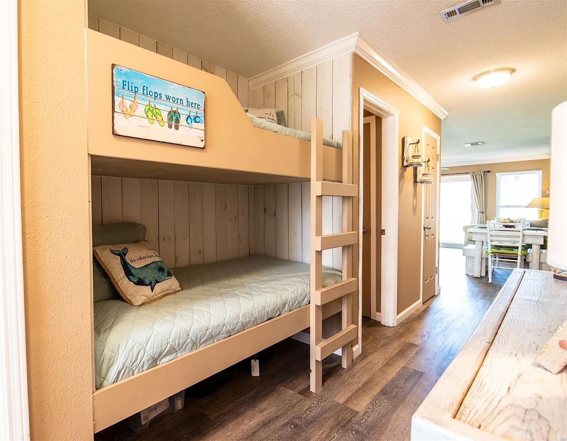 A bunk bed room with a wooden ladder, a small desk, and a chair.